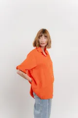 Camisa de lino color coral, de corte amplio, con cuello camisero, botones frontales y mangas 3/4 arremangables.