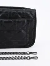Bandolera negra con diseño acolchado y correa larga de cadena plateada.