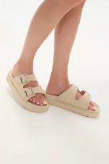 Sandalias bajas color beige con doble tira con hebilla y apliques de tachas.