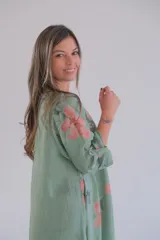 Vestido largo verde con estampado floral en tonos rosados y blancos, mangas 3/4 con ajuste de botón y ruedo irregular.