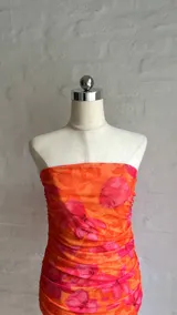 Minivestido ajustado con estampado floral en tonos naranja y rojo, con escote recto y fruncido en todo el cuerpo.