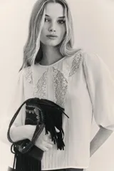 Blusa de viscosa cruda con cuello redondo, mangas largas abullonadas y detalles de encaje y puntillas en el pecho.