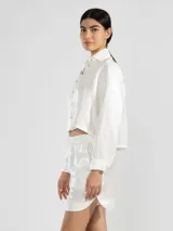 Camisa azul marino de lino italiano con hilo metalizado, cuello clásico, silueta fluida y botón en forma de flor en el cuello.