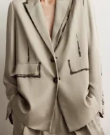 Blazer recto color topo (beige grisáceo) de viscosa, con solapa y cierre de dos botones. Presenta un diseño artístico con trazos oscuros simulando pintura en la solapa, costuras de la manga y un bolsillo de vivo con solapa en el lado derecho, mientras que el bolsillo izquierdo es pintado.