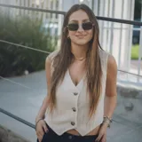 Chaleco corto color crema con escote en V, sisa redonda y cierre delantero con botones.