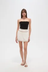 Minifalda azul marino con elástico fruncido en la cintura y el ruedo, ambos adornados con una banda de bordado étnico en tonos rosados y morados.