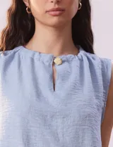 Blusa sin mangas color beige, de crepe. Cuello a la base con frunce, apertura ojal y botón.