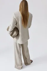 Blazer color beige de lino y viscosa, con solapas de pico, hombreras finas, cierre de un botón, pinzas en la cintura, abertura con botón en los puños, bolsillos delanteros ribeteados y abertura atrás.