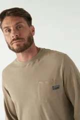 Remera color marrón de manga larga, con bolsillo en el pecho y logo de la marca en etiqueta sobre el bolsillo.