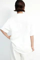Remera blanca de algodón con cuello redondo y mangas cortas. Presenta un diseño calado en el frente.