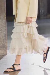Falda midi color crudo confeccionada en tejido de viscosa, con cintura elástica y volantes en capas.