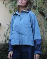 Camisa celeste de manga larga con puños elásticos y cuello camisero con detalle de flores bordadas.