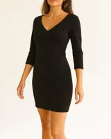 Vestido corto negro ajustado al cuerpo, con escote en V y mangas 3/4.