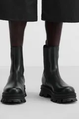Bota Chelsea de cuero negro con elásticos laterales, tirador trasero y suela track de goma.