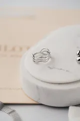 Anillo plateado de acero quirúrgico con diseño de ondas minimalista.