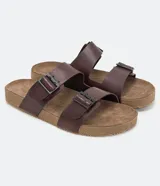 Sandalias tipo slide de cuero color marrón con dos tiras anchas ajustables con hebillas metálicas. Suela plana con textura. Marca Viko.