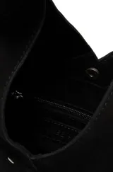 Bolso tipo hobo o media luna de gamuza negra, con un bolsillo exterior frontal decorado con tachas metálicas. El asa es ancha y está adornada con tachas a lo largo del borde superior.