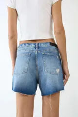 Short de denim azul con tachas plateadas, tiro alto y ruedo desflecado.