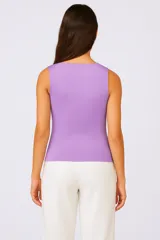 Top largo de punto color lila, ajustado al cuerpo con cuello en V y sisas con detalle ondulado.