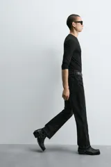 Pantalón de jean celeste de corte flare, con tiro medio, cinco bolsillos, cierre frontal con cremallera y botón, y bajo con acabado irregular.