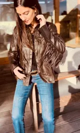 Campera marrón de cuero con cuello camisero, cierre frontal con botones a presión, bolsillos laterales y mangas largas con flecos.