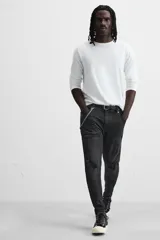 Pantalón de jean negro con corte skinny fit, cinco bolsillos, lavado con efecto roto y cierre frontal con cremallera y botón.