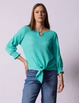 Blusa verde agua de tejido texturado marca Ruby Rd, con cuello a la base, escote en V con aplique metálico, mangas tres cuartos con puños elásticos y terminación de ruedo con nudo.