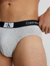 Pack de tres slips Calvin Klein en colores negro, blanco y gris, con cintura elástica negra con logo de la marca.