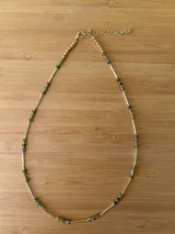 Gargantilla dorada con cuentas de cristal facetado color verde oliva y tubos dorados.