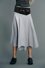 Falda midi de tiro medio con estampado de rayas verticales azules y blancas. Presenta costura de cintura asimétrica, detalle de pliegues y cierre lateral con cremallera oculta.