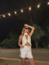 Top halter blanco de cuero sintético con detalles dorados, cuello alto y espalda descubierta.