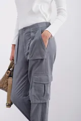 Pantalón de corderoy gris, de corte holgado, con elástico en la cintura, cierre y botón. Tiene bolsillos aplicados en el delantero y puños de piernas con elástico interno.