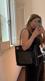 Bolso tote negro con textura símil cuero de cocodrilo, bolsillo externo color beige y asas marrones.