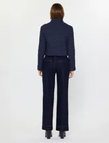 Campera corta de mujer color beige, con textura capitoneada irregular y cuello alto abotonado. Presenta cierre frontal oculto y bolsillos laterales.