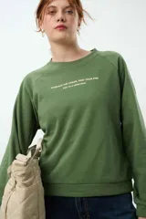 Buzo a la cadera color verde, confeccionado en suave Cotton Fleece, con ajuste holgado y mangas raglán.