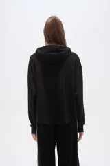 Buzo negro con capucha, cuello alto con broches, manga larga y bolsillo canguro frontal.