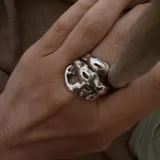 Anillo plateado con forma orgánica irregular, similar a un crustáceo marino.