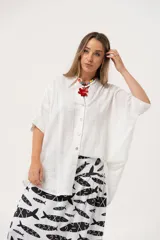 Camisa blanca con calados, escote en V, abotonada y manga 3/4.