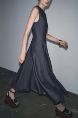 Vestido midi de denim azul oscuro, con cuello redondo y sin mangas. Corte entallado en la cintura y falda evasé. Cierre trasero con cremallera oculta.