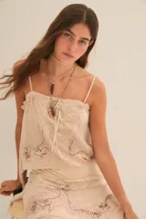 Top color crema con breteles finos, escote recto con volados y detalle de encaje en el busto. Presenta bordado de flores y lentejuelas.