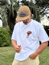 Remera blanca de algodón con estampado de un balón de fútbol americano y la frase "Together, we are America" en rojo. Incluye una firma en negro debajo del estampado.