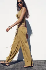 Pantalón ocre de algodón compacto, tiro medio, cintura elástica con cordón ajustable, pierna ancha y efecto lavado.