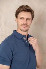 Remera tipo polo color beige, de manga corta y corte clásico. Tiene cuello con botones y está confeccionada en algodón.