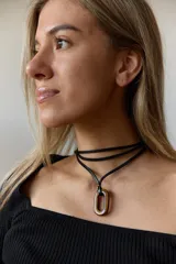 Collar con doble tira de tiento negro, una ajustada al cuello como choker y otra más larga con un dije ovalado de piedra natural blanca y un pequeño detalle dorado.