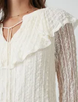 Blusa de encaje color beige de la marca Cupio, con cuello a la base y escote en V con lazo de ajuste. Presenta una sobrecapa de encaje con aplique de puntilla y mangas largas de encaje floral translúcido, terminadas en puños elásticos con volado. Incluye forro interno a tono.