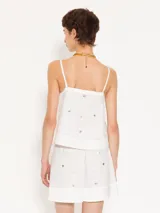 Top blanco de poplin con breteles finitos y piedras al tono en delantero y espalda. Breteles, escote y aberturas laterales terminadas con satén al tono. Cierre invisible lateral.