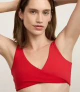 Top deportivo de microfibra color rojo, sin copa, con breteles rectos, escote en V y detalle de torcido en el busto.