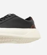 Championes casuales de cuero negro con cordones elásticos y recortes en marrón en el talón. Suela blanca.