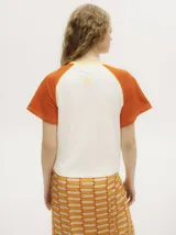 Remera colorblock con mangas ranglan color naranja, cuerpo blanco y cuello amarillo.