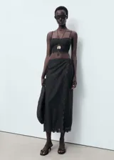 Falda midi negra con detalle de bordado calado en el ruedo y diseño cruzado.